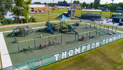 Elevated view of a fenced in playground with school children playing everywhere.