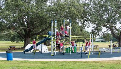 Boys in school uniforms playing on 7-post Netplex® PlayBooster play structure in a park.