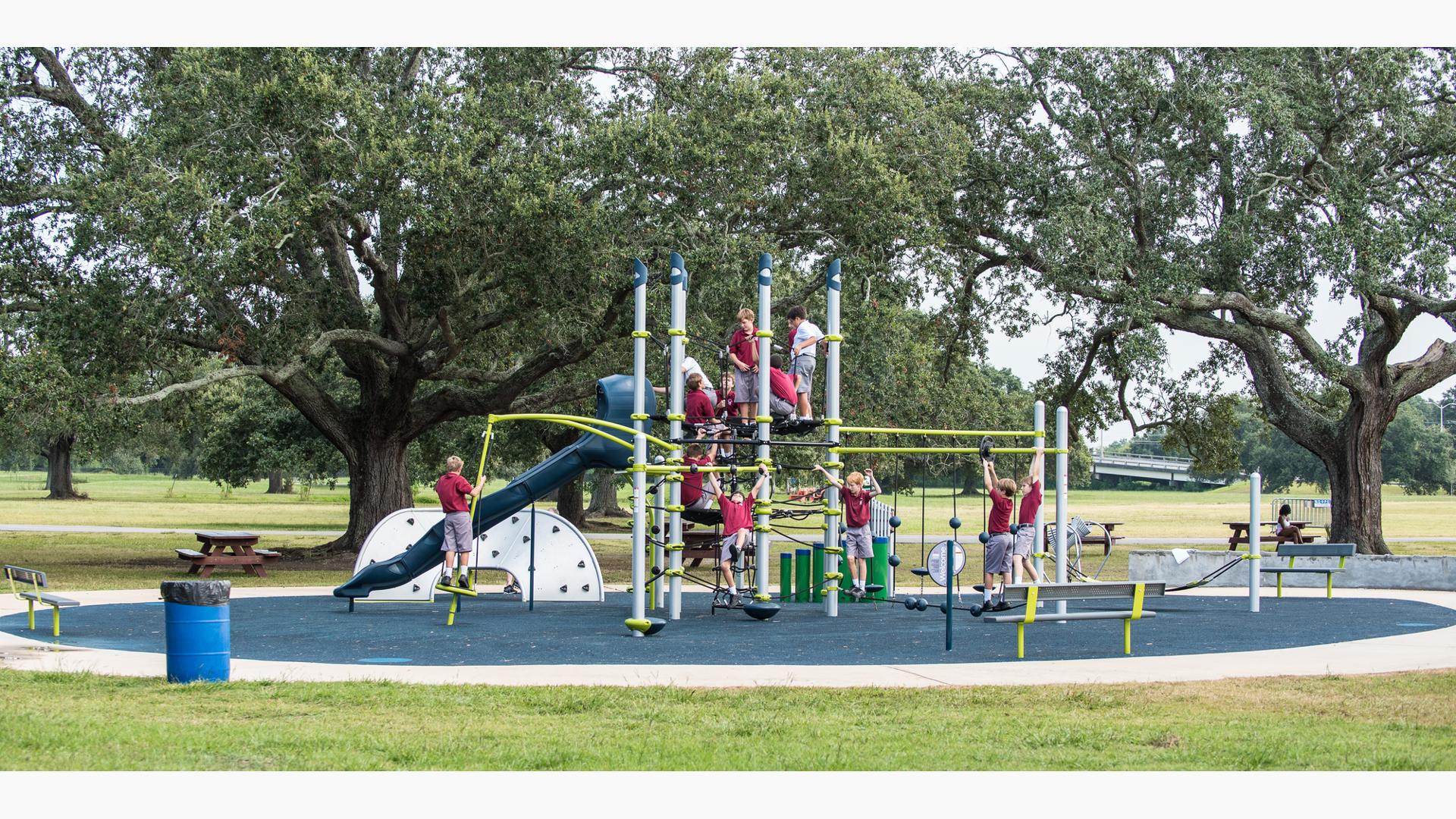 Boys in school uniforms playing on 7-post Netplex® PlayBooster play structure in a park.
