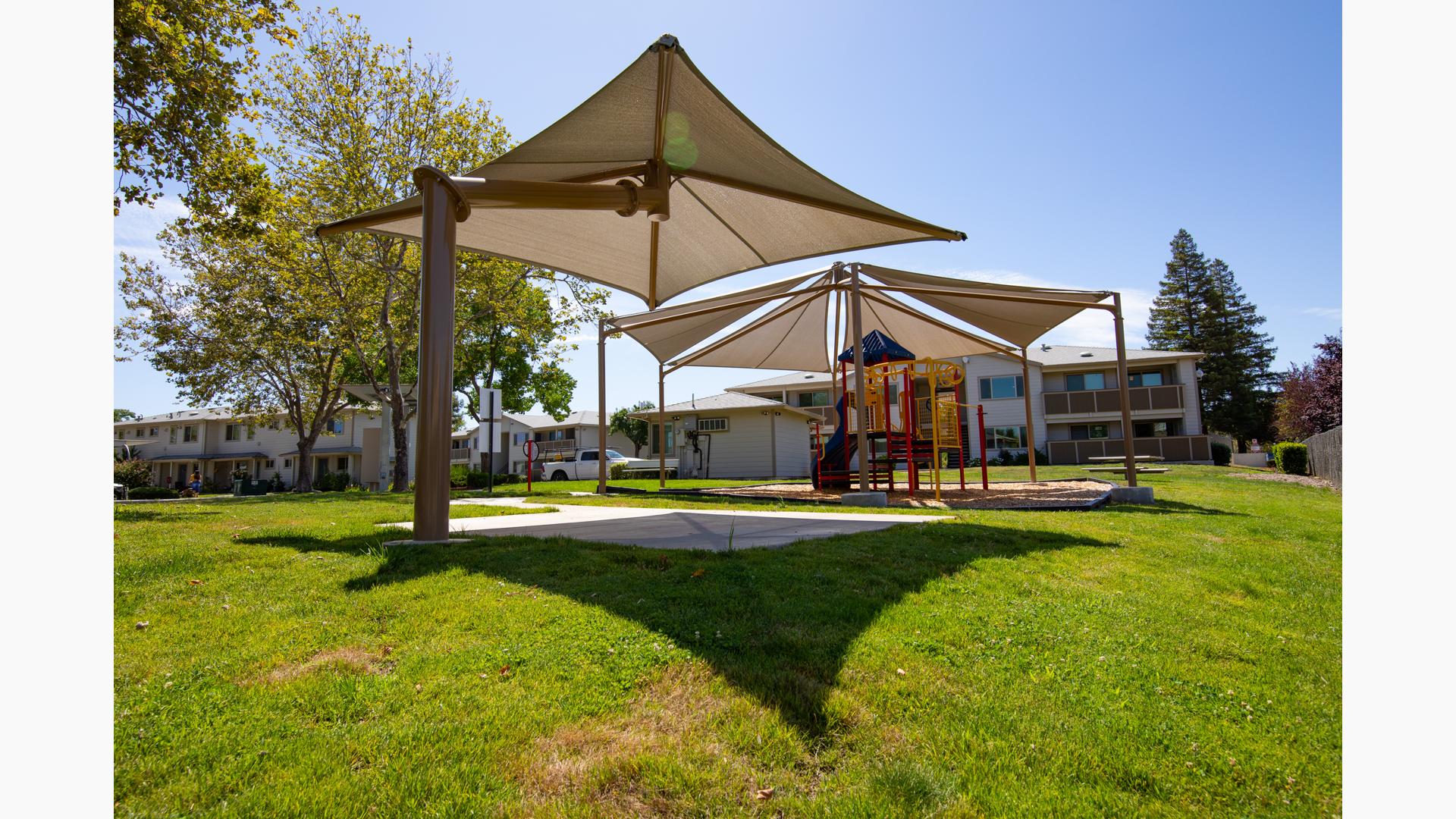 Parkview Apartments, Lincoln, CA. A PlaySense® play structure that includes playground slides, climbers, activity panels, overhead ladders, and SkyWays® shade canopies.