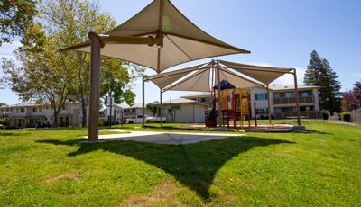 Parkview Apartments, Lincoln, CA. A PlaySense® play structure that includes playground slides, climbers, activity panels, overhead ladders, and SkyWays® shade canopies.