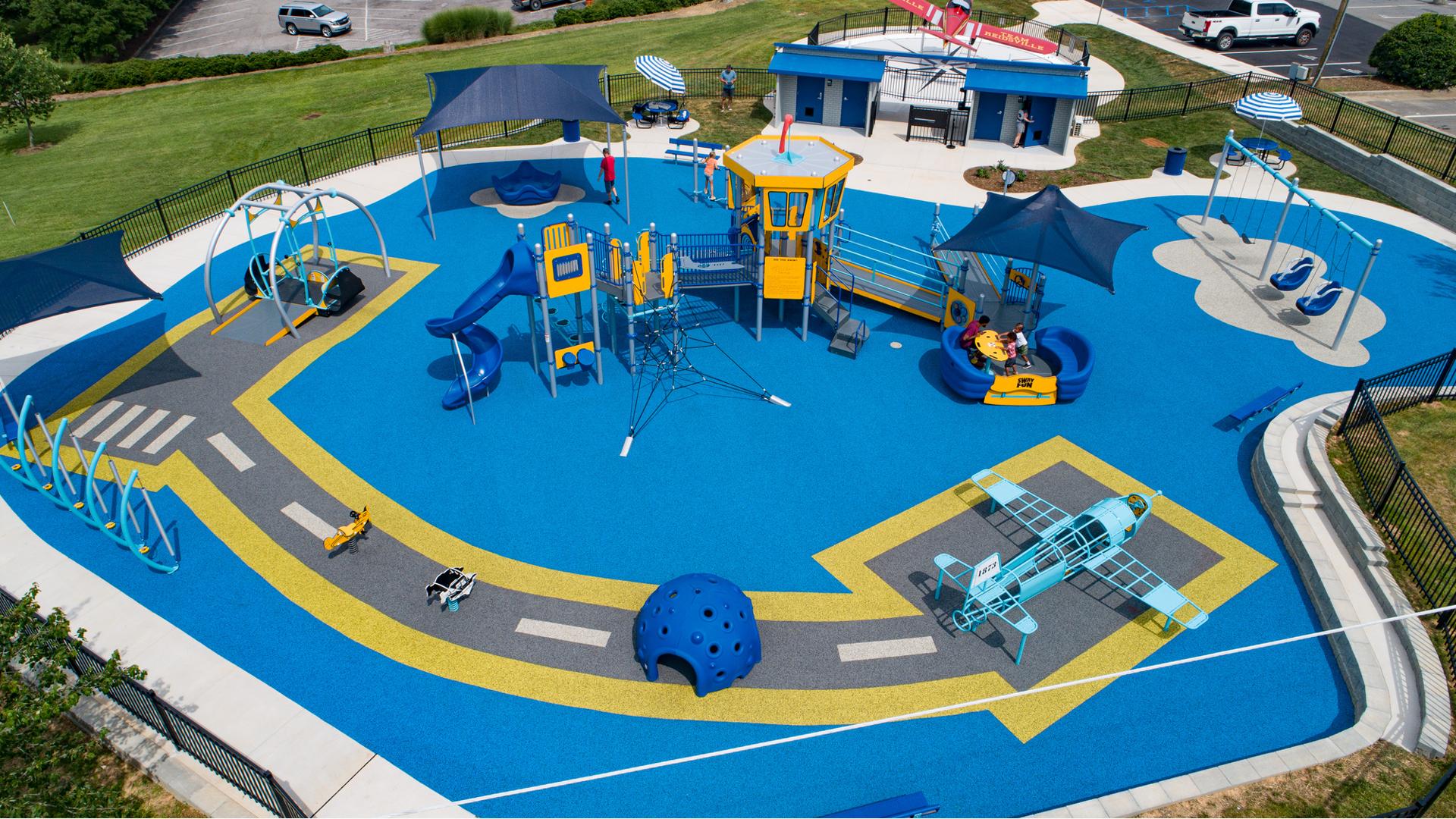 Elevated view of a airplane themed playground with control tower play structure and safety surfacing designed like a runway with custom airplane shaped play structure.