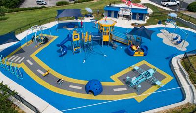 Elevated view of a airplane themed playground with control tower play structure and safety surfacing designed like a runway with custom airplane shaped play structure.