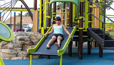 Girl in polk-a-dot shirt riding slide