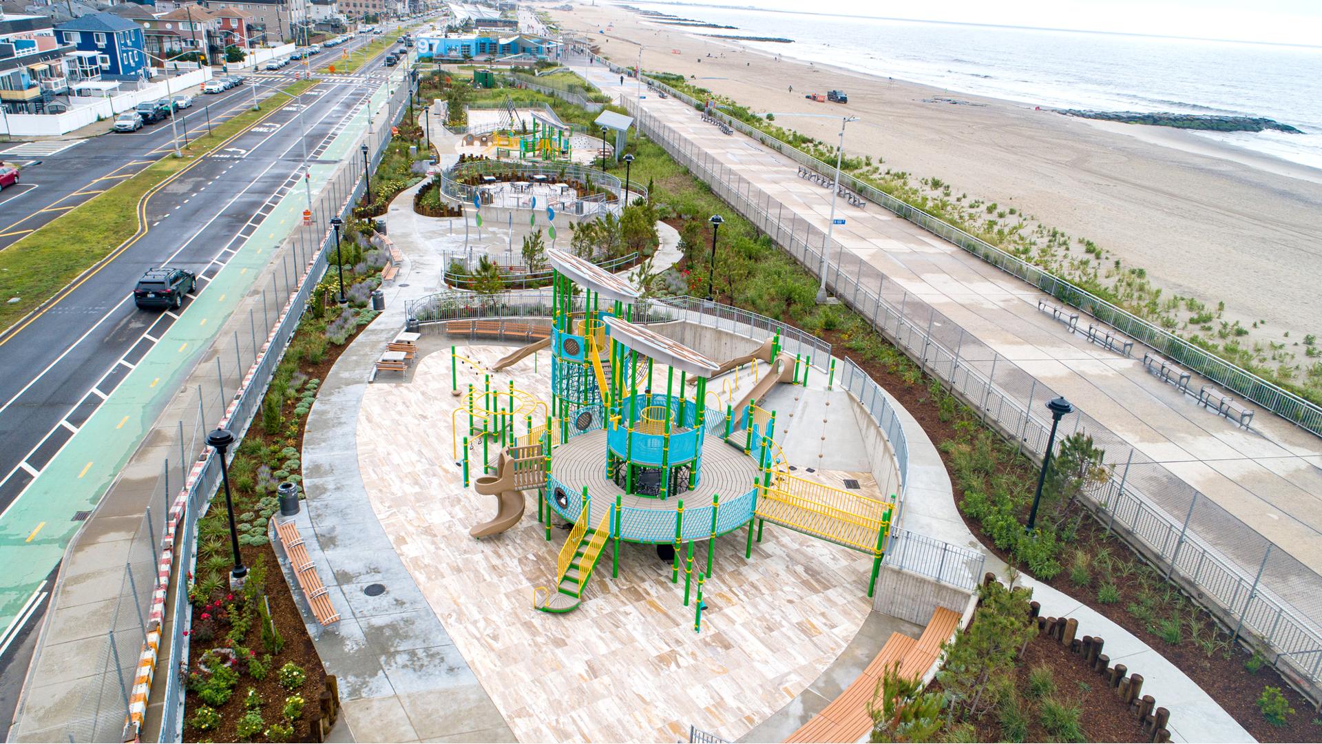 Elevated view of three separate play areas strung along an ocean beach and a city street. 