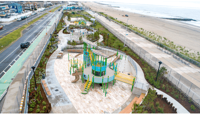 Elevated view of three separate play areas strung along an ocean beach and a city street. 