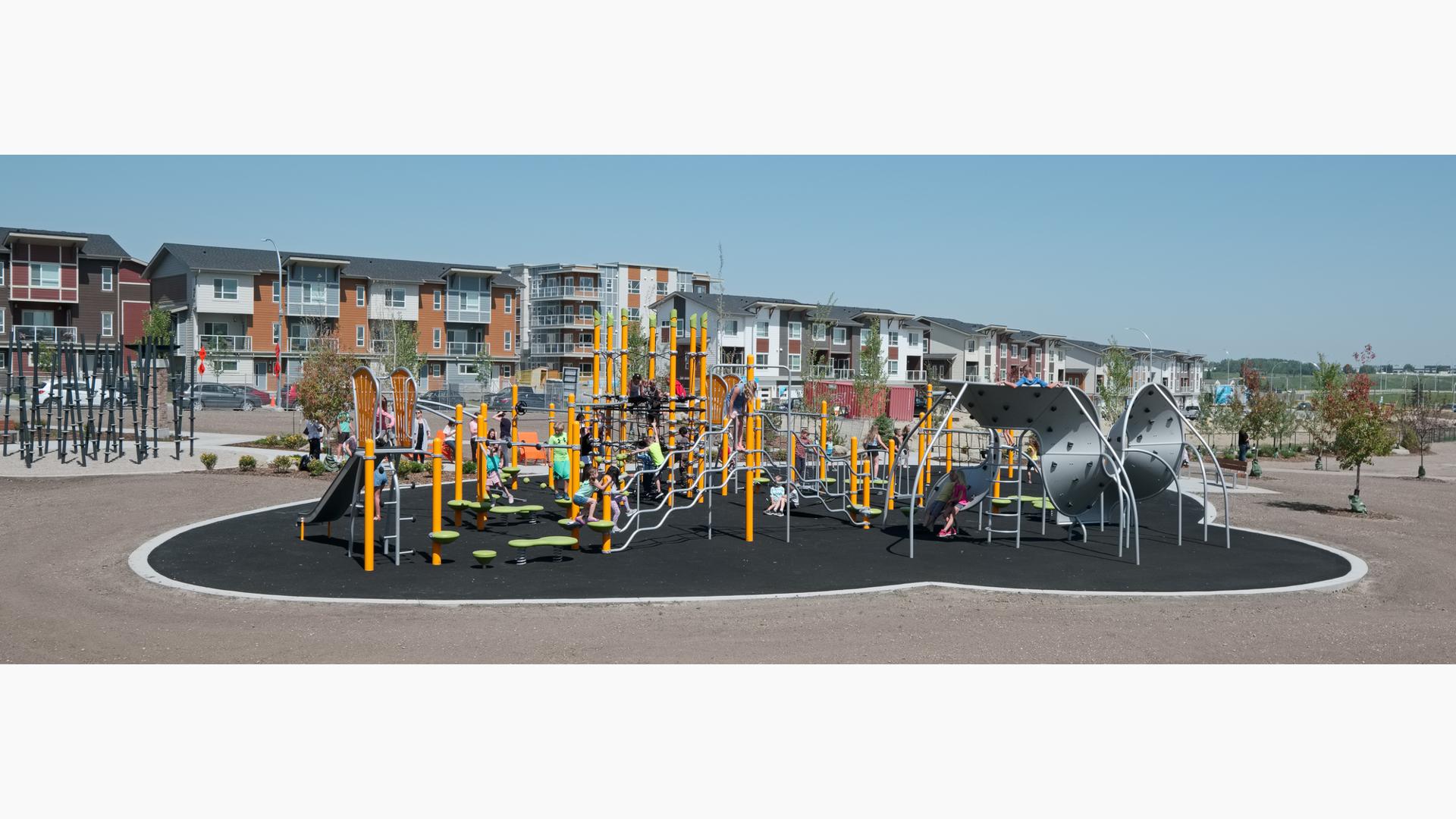 On a bright and sunny day children play at Harvest Hills Park. Climbing the 7-post Netplex play system and the 12-panel Mobius climber.