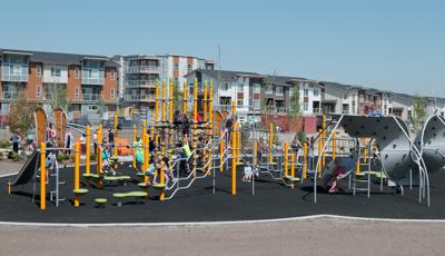 On a bright and sunny day children play at Harvest Hills Park. Climbing the 7-post Netplex play system and the 12-panel Mobius climber.