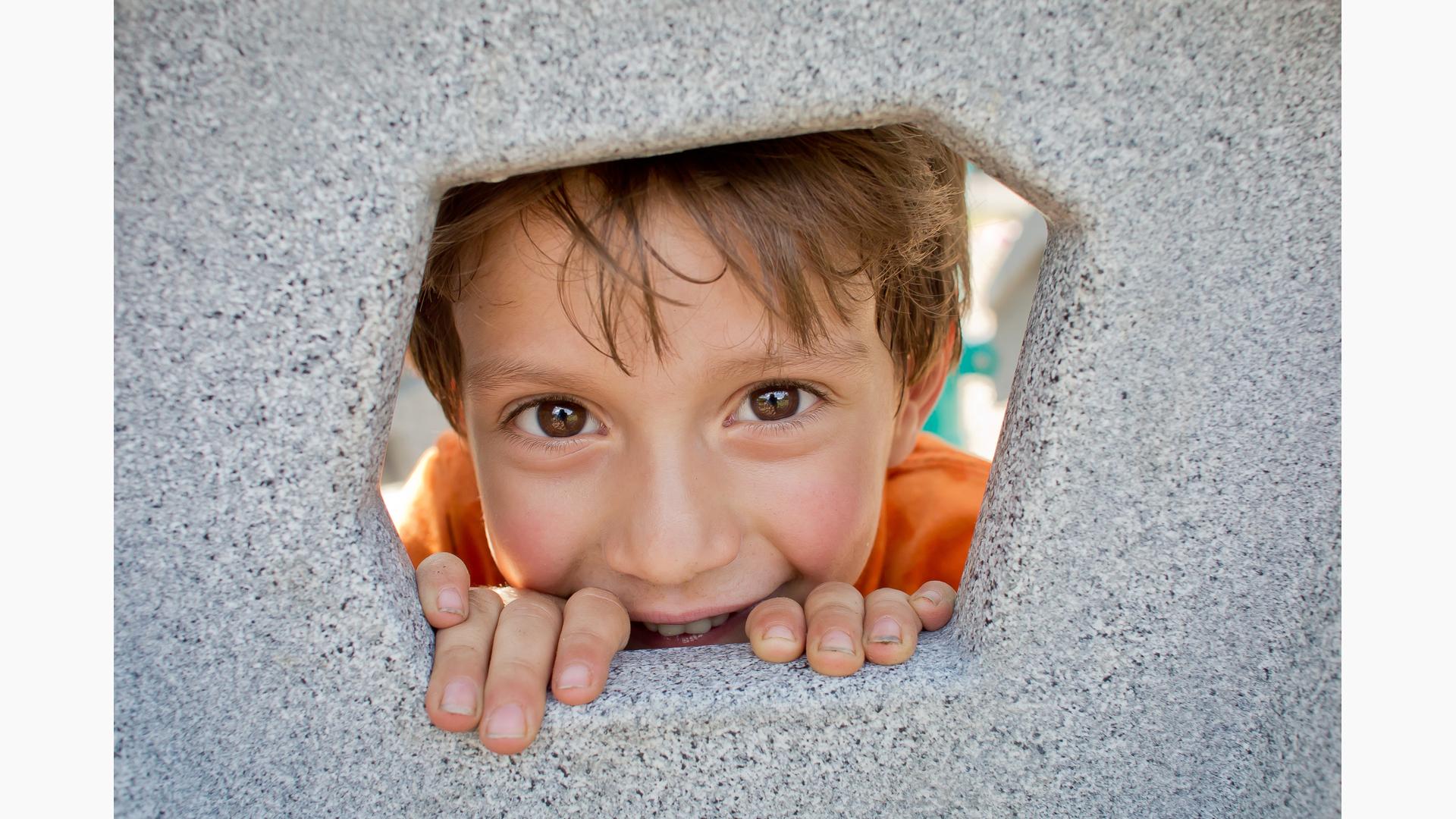 Boy smiling through hole in Geoplex Climber