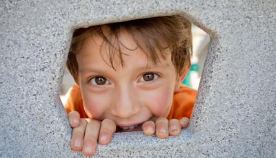 Boy smiling through hole in Geoplex Climber