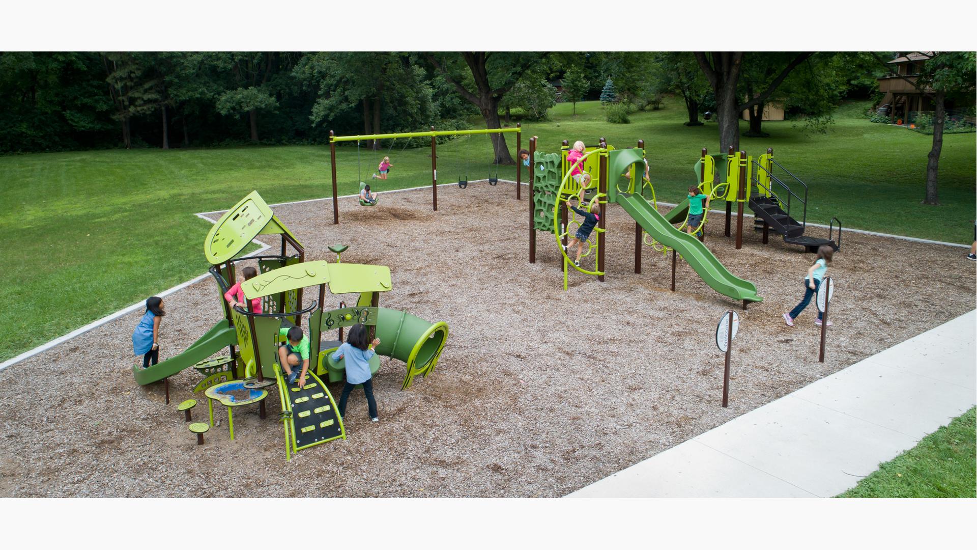 Kids playing on SmartPlay and PlayBooster structures. Two kids play on the swings.