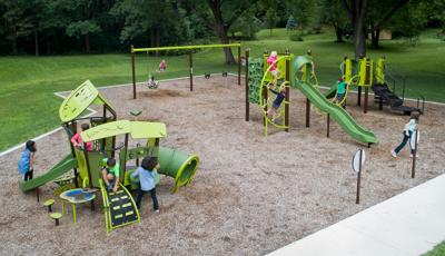 Kids playing on SmartPlay and PlayBooster structures. Two kids play on the swings.