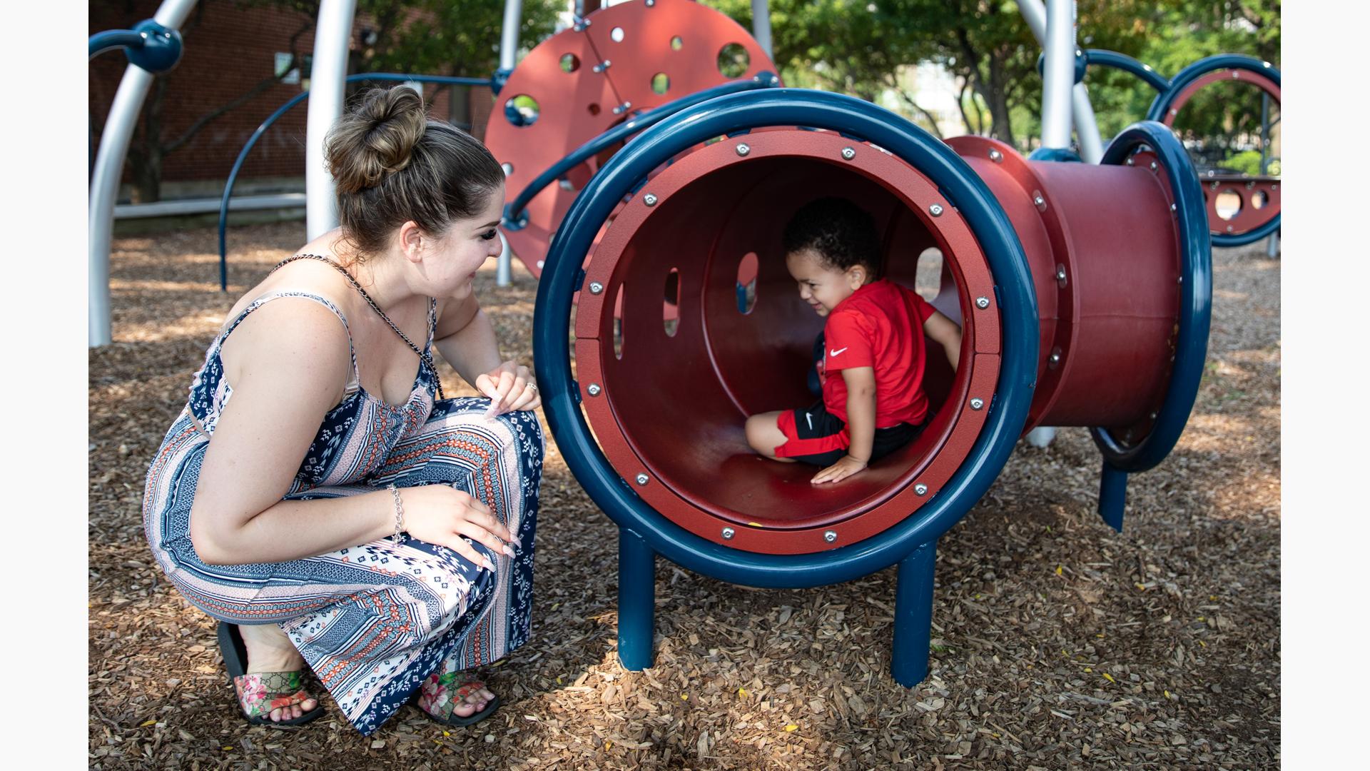 Boy playing in tunnel with mom looking in