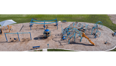 Elevated view of a park playground with blue posts as children climb through the weaving ropes and belt climbers of the play structure.