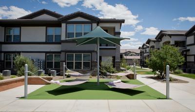 Four hammocks tied to a center post with green shade in residential courtyard. 