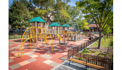 Wheelchair accessible, ramped playground structure with three green roofs and yellow climbers.