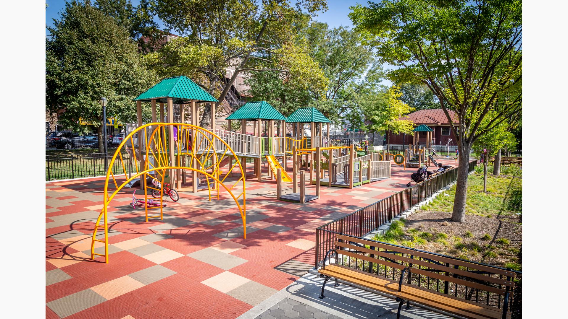 Wheelchair accessible, ramped playground structure with three green roofs and yellow climbers.
