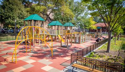 Wheelchair accessible, ramped playground structure with three green roofs and yellow climbers.