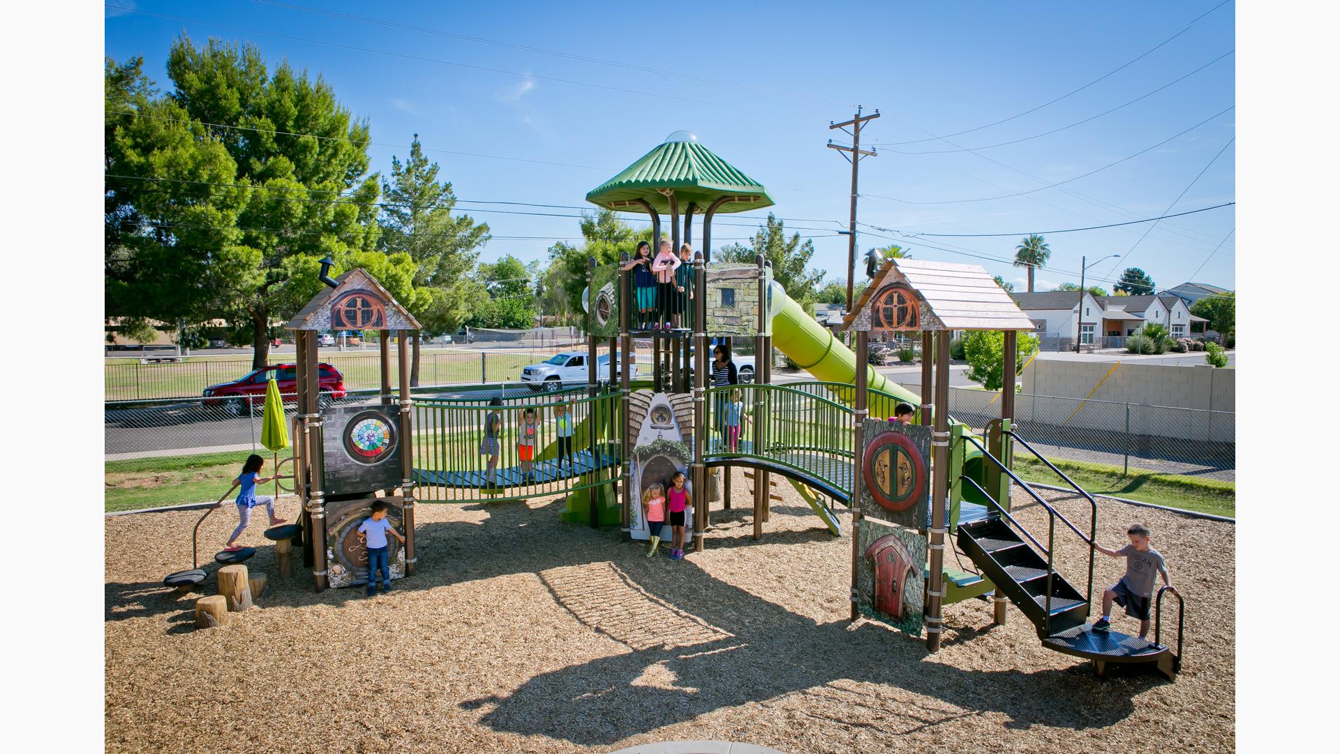 Children of Villa Montessori School playing on medieval-themed play structure. The bridges make it fun and easy to go from one castle to another. A group of children stand at the top point, near the tunnel slide, while other kids play on the ground level.