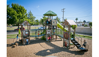 Children of Villa Montessori School playing on medieval-themed play structure. The bridges make it fun and easy to go from one castle to another. A group of children stand at the top point, near the tunnel slide, while other kids play on the ground level.