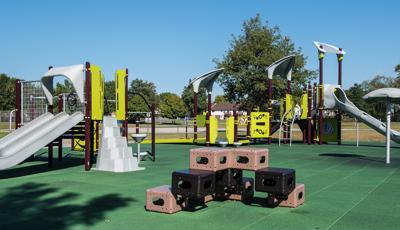 Modern-looking playground for kids ages 5 to 12 over green safety surfacing