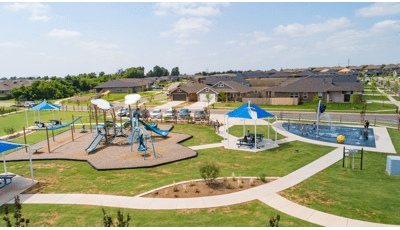 Elevated view of a community park with a cloud and wind themed playground on the left and a space themed splash pad on the right.