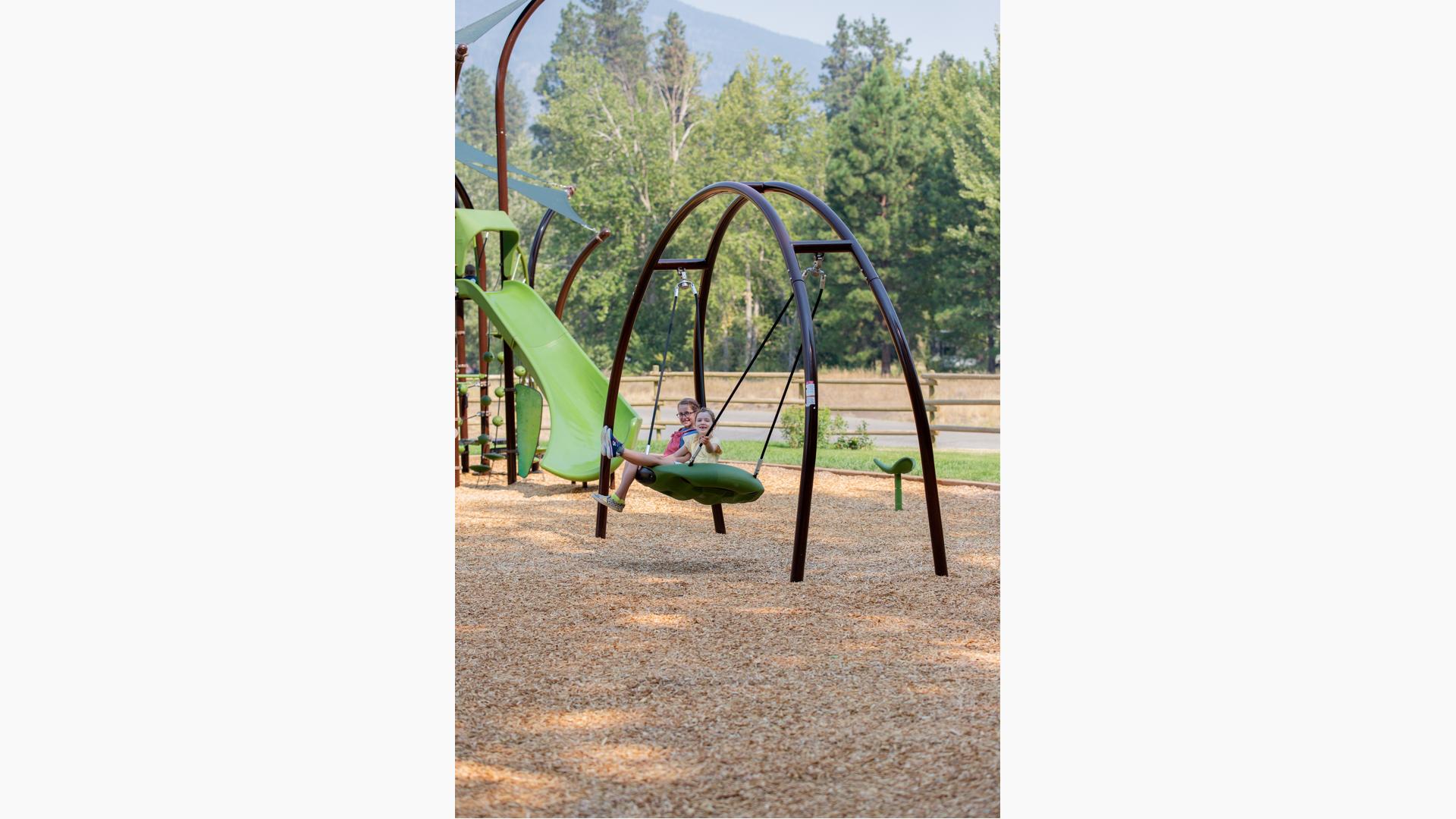 Two girls sitting and smiling on Oodle® Swing