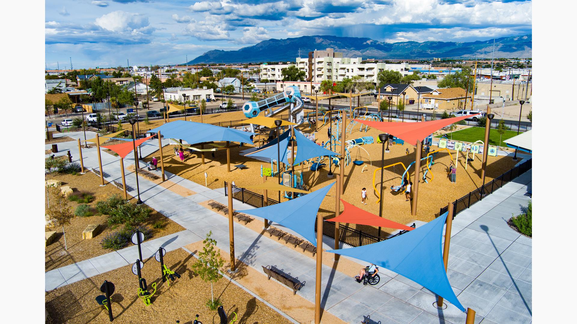 Elevated view of a large play area with play structures and scattered shade sails covering structures and play activities.