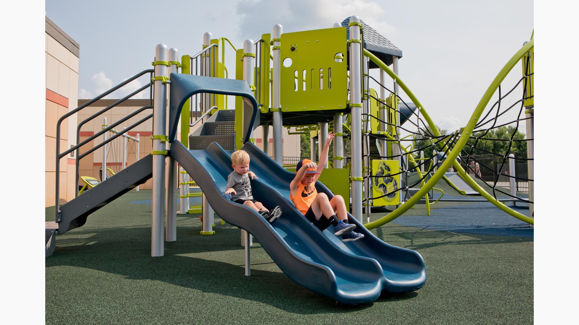 Two boys riding Double Wave slide