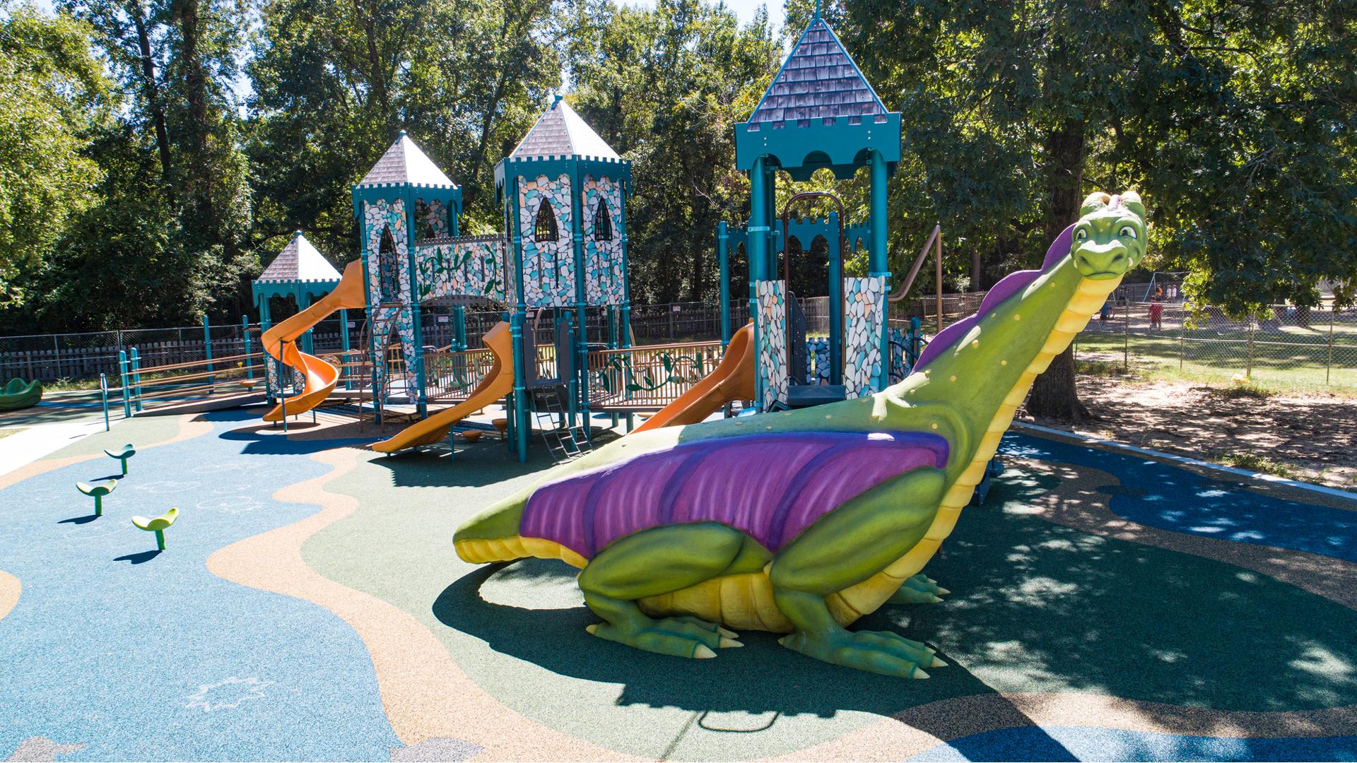 A full sized colorful dragon made of concrete allows children to climb up to the castle themed play structure.