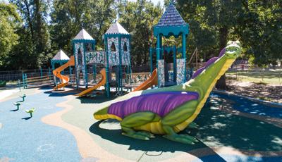 A full sized colorful dragon made of concrete allows children to climb up to the castle themed play structure.