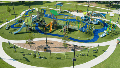 Elevated view of a large park play space with many playground structures, activities and a work-out section.