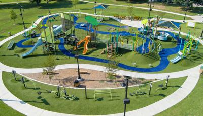 Elevated view of a large park play space with many playground structures, activities and a work-out section.