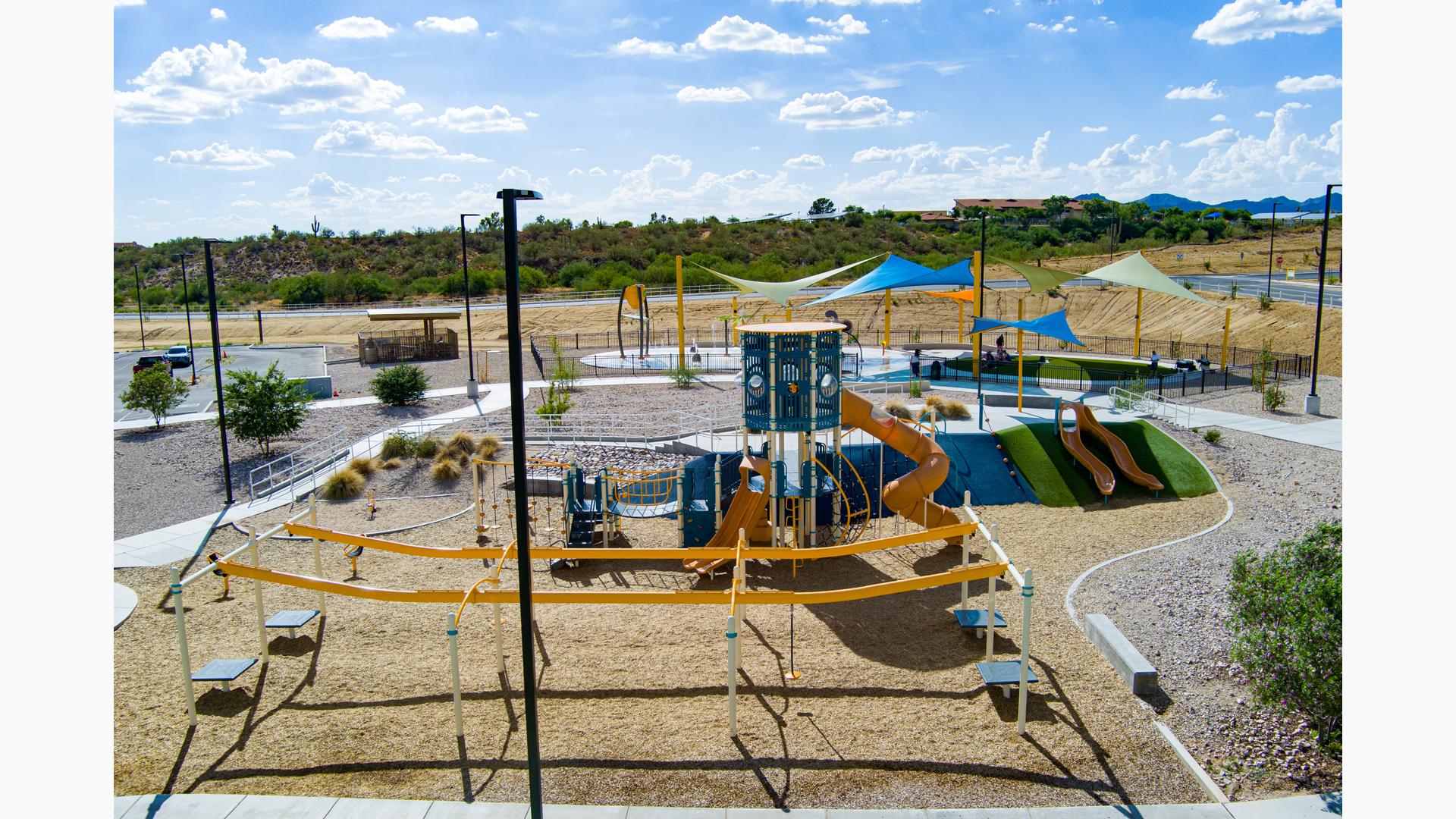 Elevated view of a park playground with a splash pad in the background.