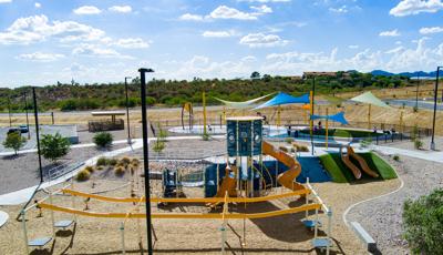 Elevated view of a park playground with a splash pad in the background.