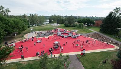 View over Shouldice Park. Families play on the Global Motion, the many swings and run along the access ramps.