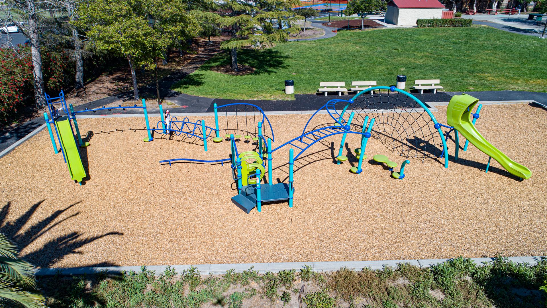 Full elevated view of a long continues play area with connecting climbers, slides, and other playground activities allowing for a continues play experience.