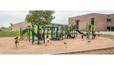 It is a cloudy day as kids at Stanley Knowles School play on the playground. A girl runs to the back of the line for the ZipKruz. Another girl uses the Gyro Twister Spinner. A group of children gather at the top of the slide.