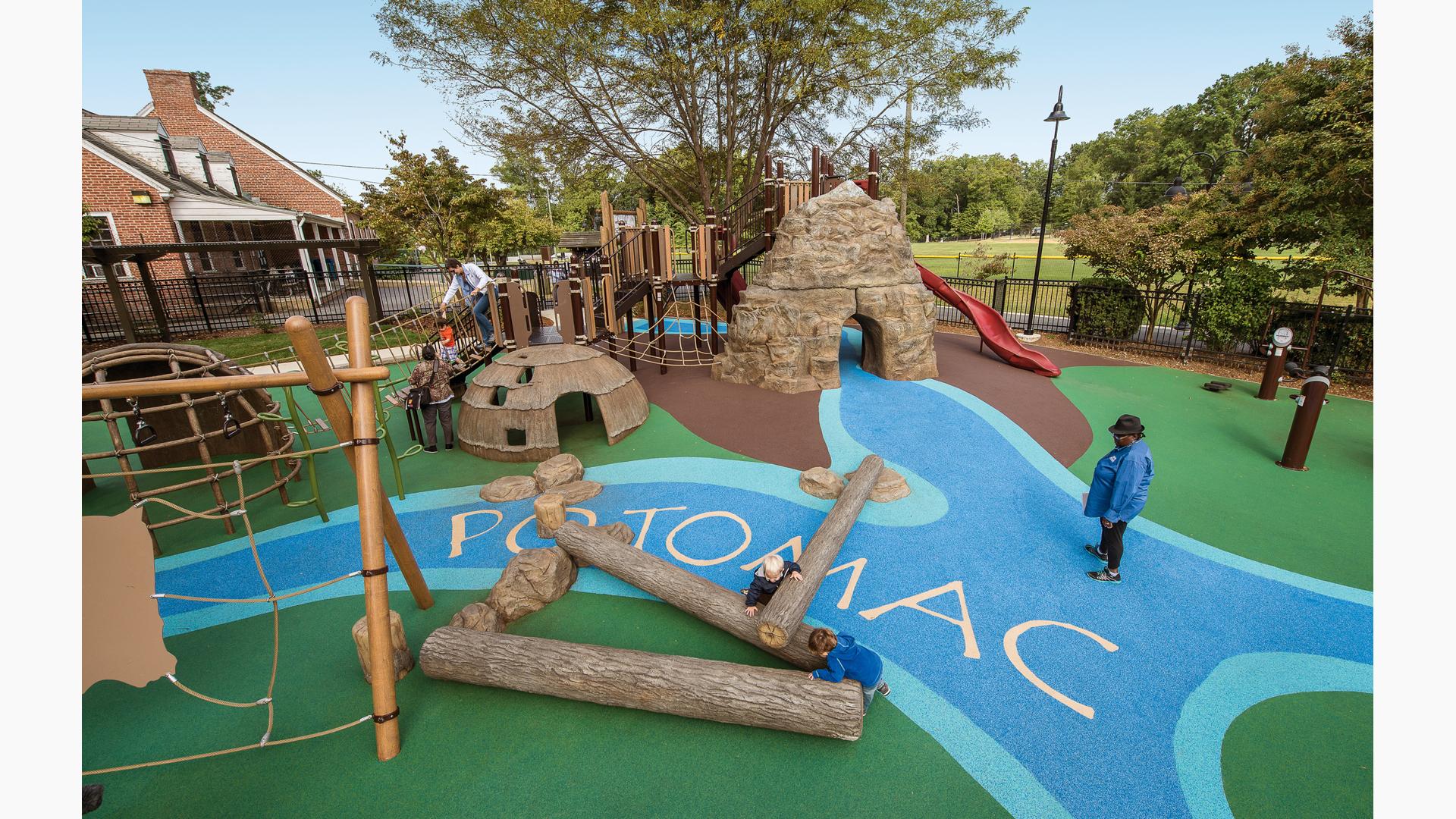 A woman stands on a replica of the Potomac river that lays on the grounds of Palisades Recreation Center park. It connects components of the playground as a family crossed the rope bridge.