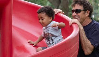 Dad watches boy ride down slide