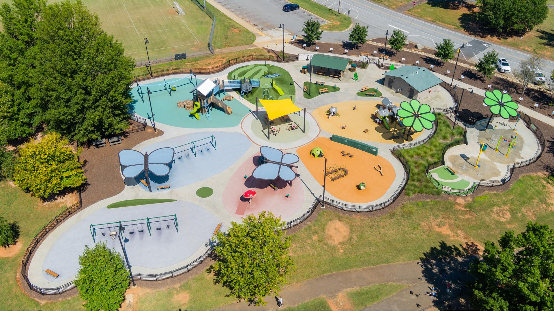 Elevated view of a flower shaped play space with play structures, flower and butterfly shaped shade systems and a splash pad.