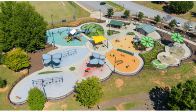 Elevated view of a flower shaped play space with play structures, flower and butterfly shaped shade systems and a splash pad.