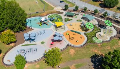 Elevated view of a flower shaped play space with play structures, flower and butterfly shaped shade systems and a splash pad.