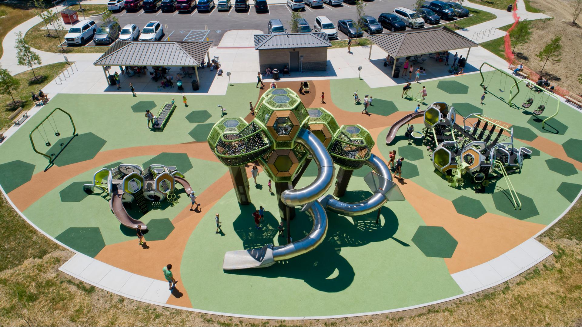 Elevated view of a park playground with play structures made of hexagonal connecting pods and other surrounding play activities.
