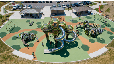 Elevated view of a park playground with play structures made of hexagonal connecting pods and other surrounding play activities.