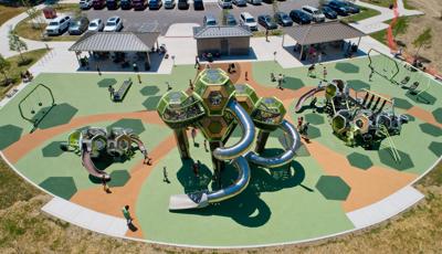 Elevated view of a park playground with play structures made of hexagonal connecting pods and other surrounding play activities.