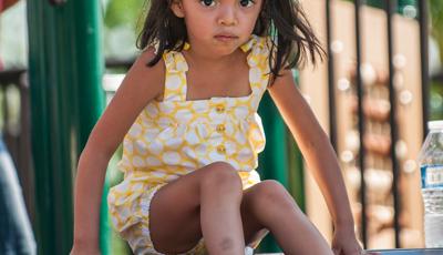 Girl in yellow outfit sitting on top of rollerslide