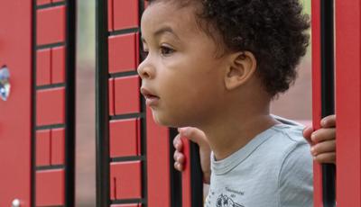 Toddler boy sticks his head out of play structure