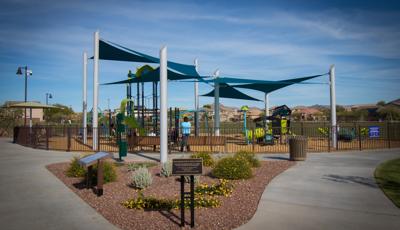 Parents watch from benches as their kids play on the PlayBooster and Smart Play  play systems. SkyWays shade panels cover the playground.