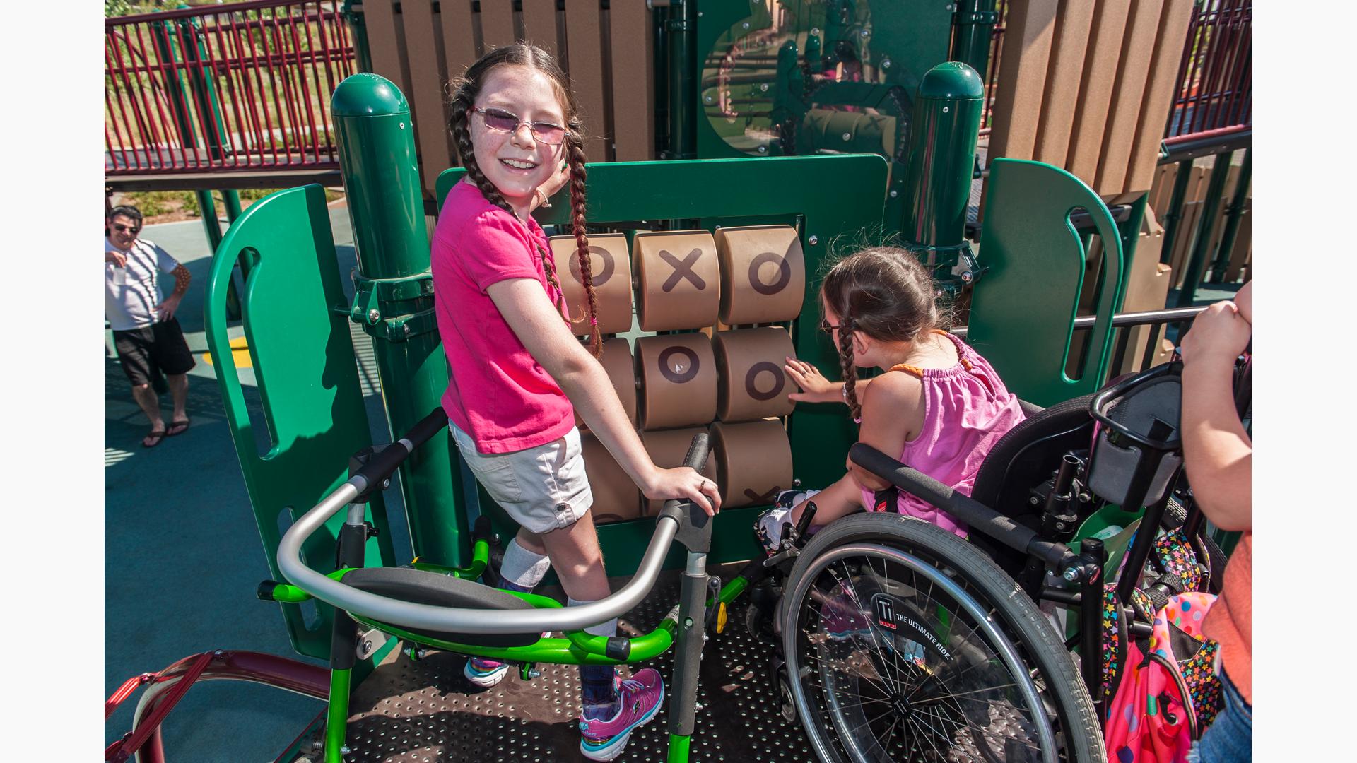 Girl smiling as she plays on tic-tac-toe panel with a friend